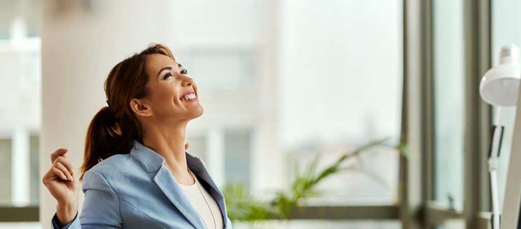 Happy businesswoman stretching while working at her office desk