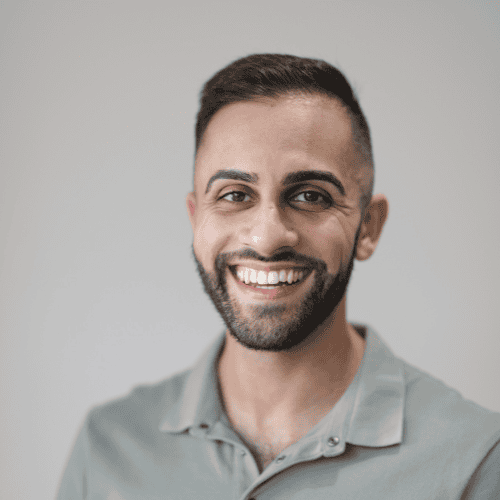 Smiling man with short dark hair and beard in a grey shirt, portrait image for Therapia.