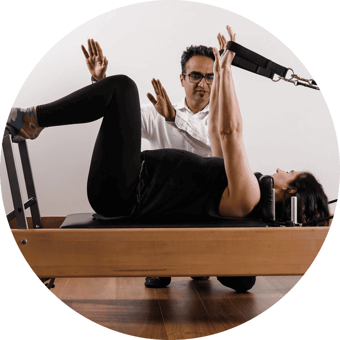 Gentle physiotherapy session with a therapist assisting a woman on a reformer machine.